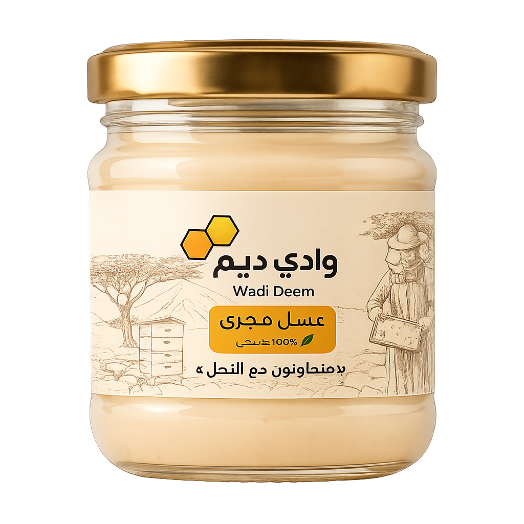 عبوة عسل المجرى من وادي ديم بلون كريمي فاتح موضوعة فوق صخرة جبلية ومحاطة بأزهار المجرى البيضاء والجبال الطبيعية في الخلفية.